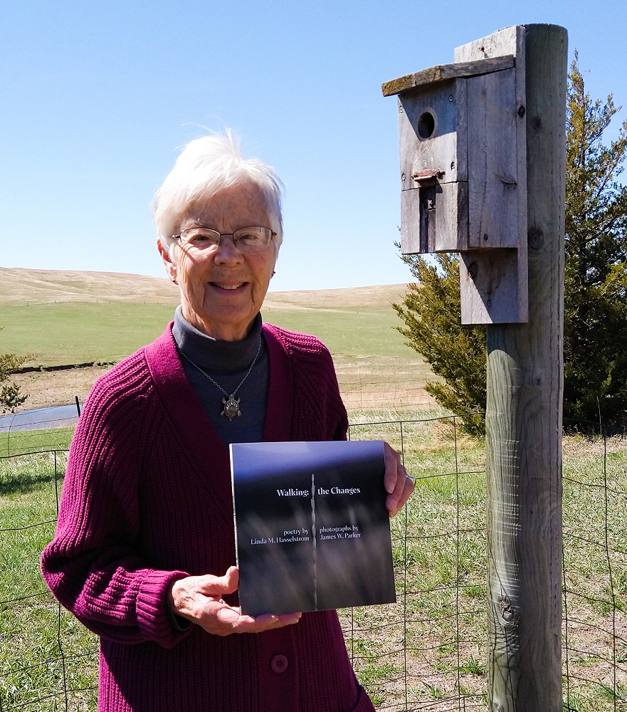 Image of Linda Hasselstrom smiling and holding up her newest book Write Now, Here's How.